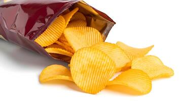Open bag of rippled potato chips spilling out onto a black surface in a close up studio shot photo