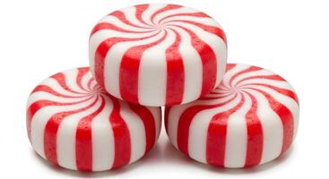 A close up of a stack of three peppermint candies with red and white stripes on a black background photo