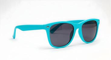 A pair of turquoise sunglasses with dark lenses isolated against a black background in studio shot photo