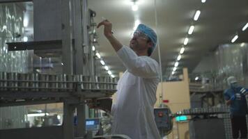 The production control supervisor inspects and controls the operation of machines in the manufacturing line of a canned fish industry video