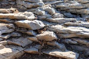 Natural stone formation with layered textures and earthy tones in a rugged outdoor setting photo