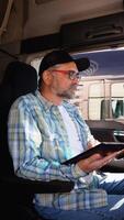 Senior truck driver using truck gps navigation to looks the route before leaving. Vertical video