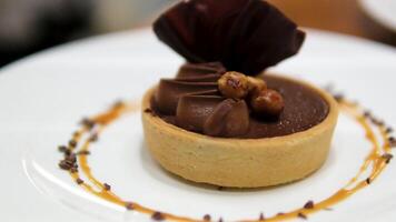 Delicious homemade chocolate tarts named Amandines in frensh surrounded by walnuts and almonds being presented on a table video