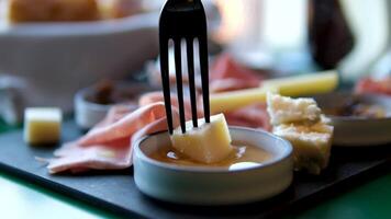 dip cheese in honey Piece of delicious blue cheese on the fork is dipped into fresh honey in a glass jar on a sunny summer day video