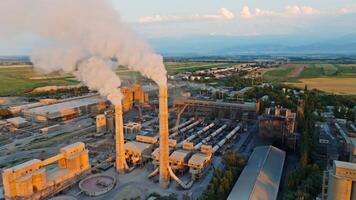 aerial view of two smoking pipes of soviet concrete factory at sunset, is this unique title video