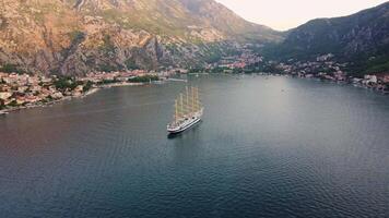 Kotor, Montenegro, 08-27-2024, Aerial view of the Star Clipper sailing ship in the Bay of Kotor in the Adriatic Sea at sunset. The ship is set against the backdrop of the tourist town of Kotor video