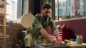 Caucasian craftsman man male guy businessman potter small business owner wet hands water work with clay material brown mud pottery shaping molding stoneware manufacturing hobby indoor workshop studio video