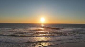 Golden sunset over ocean with aerial view of waves and empty beach video