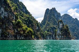 High rocky cliff trees covered in the lake of Thailand with clouds photo