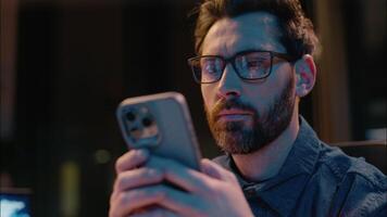 Caucasian man business entrepreneur manager at dark night evening office overtime working male guy concentrated businessman ceo trader browsing smartphone gadget addict insomnia typing mobile phone video