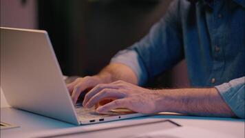 Overtime night working Indian businessman male guy manager business man at dark evening office working with laptop computer browsing at desk smiling employer worker programming online commerce project video