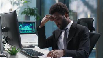 Tired African American man working web online with computer businessman male bored guy business depressed unhappy sad manager employer entrepreneur in office exhausted worker fatigue overwork indoor video