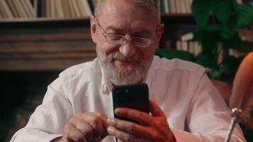 Old Caucasian man using mobile phone smartphone male mature senior gadget businessman smiling digital device business home online internet social media chatting indoor office addict pensioner browsing video