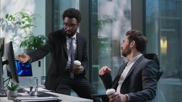 Two multiethnic African American Caucasian men coworkers colleagues friends buddies businessmen talking discuss computer project break pause workplace business diverse males drinking coffee in office video