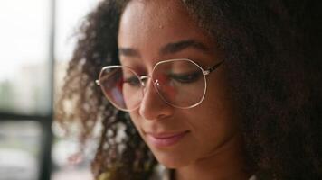 Close up portrait thinking African American girl student in university beautiful clever ethnic woman female smiling looking at camera wearing glasses in class exam preparations authentic lady study video