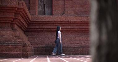 Handheld low angle view shot, Solo female tourist enjoys strolling around to appreciate the serene surroundings and the cultural richness of the place. Leisure tourism video