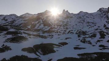 Aerial shot - Sunlight illuminating snow covered Pyrenees mountain peaks, creating dramatic shadows across pristine winter alpine landscape video