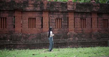Handheld side view shot, Female tourist enjoys taking photos with camera while taking a leisurely stroll amidst serene surroundings and the cultural richness of the place. video