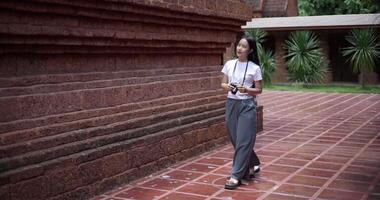 Handheld shot ,An Asian female tourist walks around the temple grounds and takes photos. video