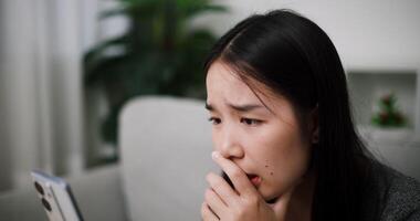 Handheld selective focus shot, Young Asian woman is having a heated argument with her boyfriend over a call while sitting on a sofa. Relationship problems video