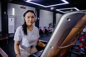 Attractive woman on treadmill enjoys music using headphones in g photo