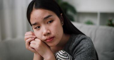 Handheld shot, A sad young woman sits alone on a sofa at home, looking anxious and lost in thought. video
