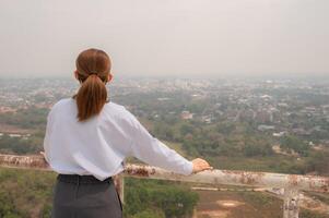 Rear view of Asian businesswoman looking to her hometown cover by bad air pollution. photo