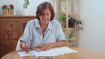 Senior woman counting coins and reviewing bills at home video