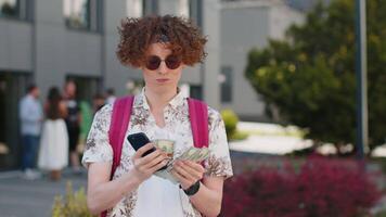 Happy rich tourist man counting holding money dollar cash, use smartphone calculator app outdoors video