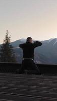 Man meditating in the mountains, peaceful winter scenery with trees and snowy peaks video