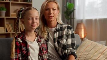 Caucasian family child schoolgirl looking at camera demonstrating thumb down upset little kid mother discontent sad mom woman female showing negative response parent daughter denial no gesture at home video