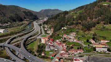 Mountain highway interchange with river and rural village, aerial view video