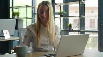 Caucasian woman girl working with laptop typing business project browsing computer relaxed professional businesswoman at desk drink tea office coffee break stretching hands rest leaning on chair pause video