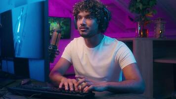 Arabian Latina man playing computer male vlogger streamer discuss gamer speak mic addict influencer happy guy digital game blog at home cyber sport neon host e-sport radio presenter broadcast online video