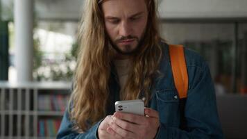 Caucasian student guy man male using smartphone laughing winning with mobile phone app yelling celebrate in university chatting receive good news victory internet achieve betting in college hallway video