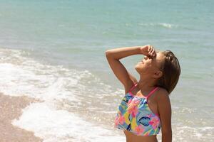 Child Covering Face from Sun at Seaside photo