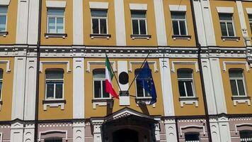 Flag of Italy and the European Union on the facade of the embassy house. Colorful banners flutter in the wind against a building in Kyiv, Ukraine. video