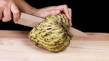 Hands slicing a custard apple on table video