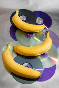 Bananas rest on reflective CDs, merging retro tech nostalgia with tropical vibes, perfect for Intergalactic Technology Day or Fruit Festival photo