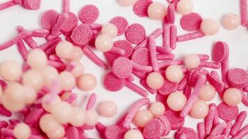 Pink and peach sprinkles cascade onto a white surface, captured in extreme close-up with bright lighting video