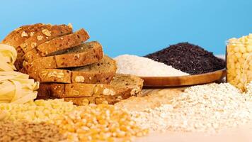 A variety of grains, pasta, and bread arranged against a vibrant blue backdrop. Bright lighting enhances the textures and colors video