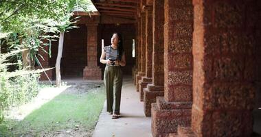 Handheld shot, Happy woman walking exploring and enjoying taking photos at an ancient site, Enjoy holiday travel. video