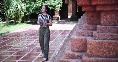 Happy young woman in casual clothes walking exploring and enjoying taking photos at an ancient site, Enjoy travel. video