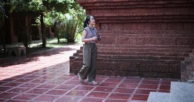 Handheld shot, Young Asian woman in casual clothes walking exploring and enjoying taking photos at an ancient site, Enjoy holiday travel. video