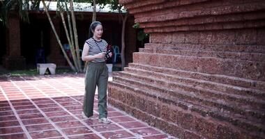 Handheld shot, Happy young woman in casual clothes walking exploring and enjoying taking photos at an ancient site. video