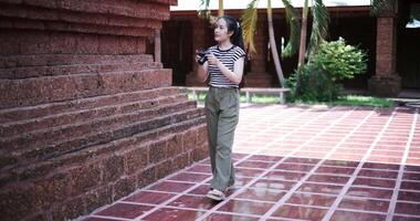 Handheld shot, Happy young woman in casual clothes walking exploring and enjoying taking photos at an ancient site, Enjoy travel. video