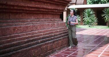 Handheld shot, Happy Asian woman in casual clothes walking exploring and enjoying taking photos at an ancient site, Enjoy holiday travel. video