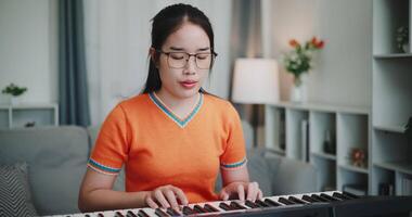 Medium shot, Asian woman is relaxing and enjoying playing music on an electronic keyboard in a quiet house. Leisure activities at home video