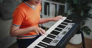 High angle view shot, Asian woman playing the keyboard with happy smile in cozy living room. Enjoy a relaxing weekend activity video