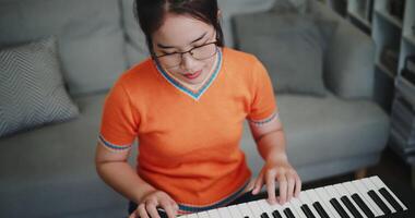 High angle view shot, Beautiful Asian woman playing the keyboard with happy smile in cozy living room. Enjoy a relaxing weekend activity video